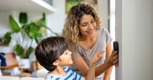 Mother and son at home using a smart thermostat