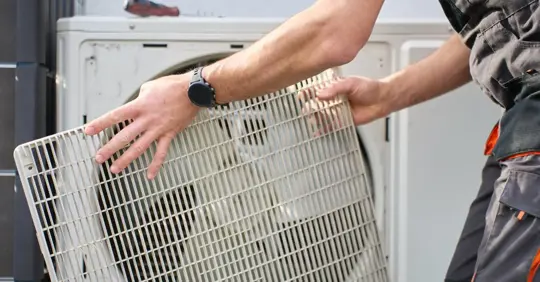 Technician removing cover from outdoor heat pump unit